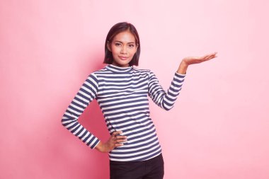 Pembe arka planda eli olan genç bir Asyalı kadın var.