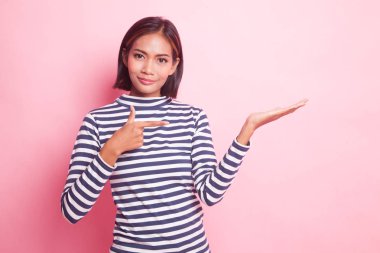 Güzel genç Asyalı kadın pembe arka planda el ele tutuşuyor.