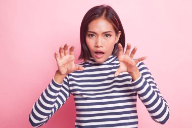 Pembe bir arka plan üzerinde ürkütücü el hareketi ile genç Asyalı kadın