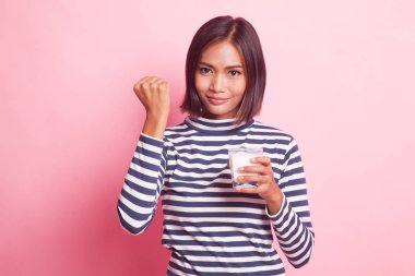Sağlıklı Asyalı kadın pembe arka planda bir bardak süt içiyor.