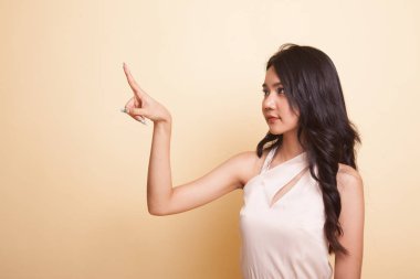 Asyalı kadın bej arka planda parmaklarıyla ekrana dokunuyor.