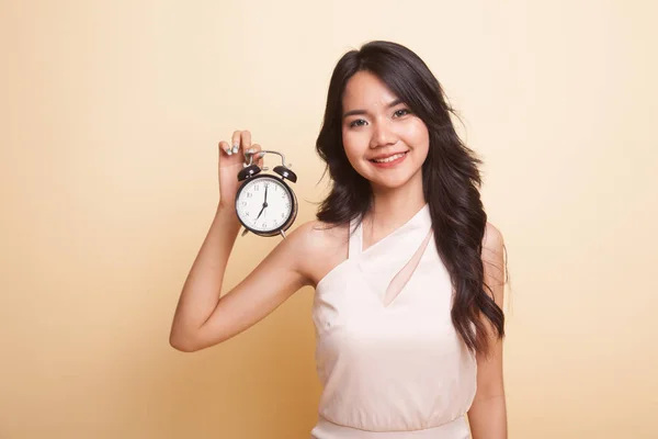 Young Asian woman with a clock  on beige background