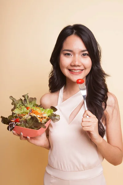 Healthy Asian woman with salad  on beige background