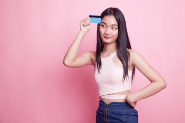 Genç Asyalı kadın pembe arka planda boş bir kartla düşünüyor.