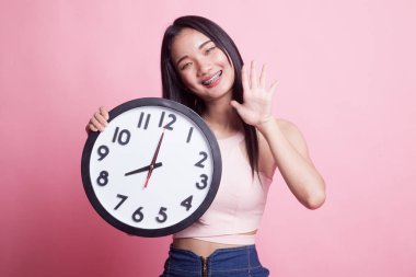 Mutlu genç Asyalı kadın ile pembe bir arka plan üzerinde bir saat