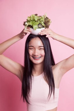 Pembe arka planda salatası olan sağlıklı Asyalı kadın.