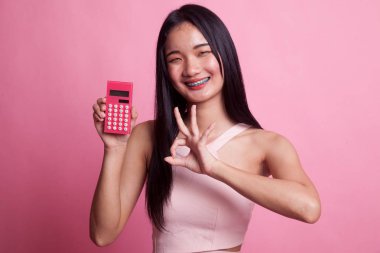 Asyalı kadın pembe arka planda hesap makinesiyle iyi görünüyor