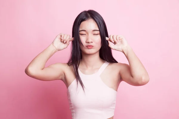 年轻的亚裔妇女在粉红色背景下用手指挡住耳朵 — 图库照片