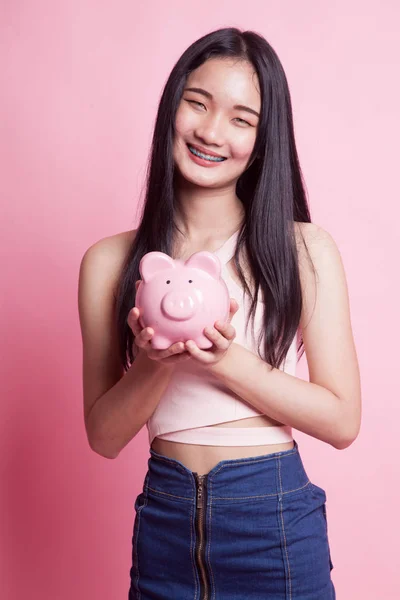 Pembe Arka Planda Domuz Sikkesi Bankası Olan Genç Asyalı Kadın — Stok fotoğraf