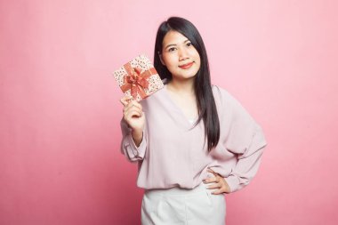 Pembe arka planda hediye kutusu olan genç bir Asyalı kadın.