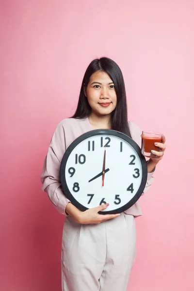 年轻的亚洲妇女与蕃茄汁液和时钟在粉红色背景 — 图库照片