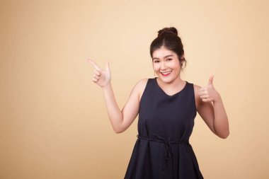 Genç Asyalı kadın bej arkaplanı işaret ediyor ve onaylıyor