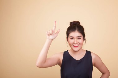 Asyalı kadın bej arka planda parmaklarıyla ekrana dokunuyor.