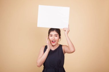 Genç Asyalı kadın sürprizi bej arka planda beyaz boş işareti var.