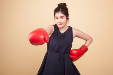 Bej arka planda kırmızı boks eldivenli genç Asyalı kadın.