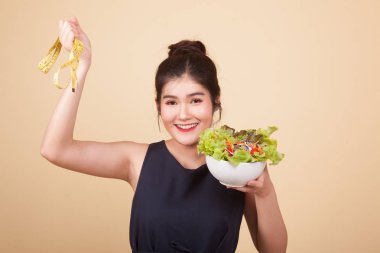 Teyp ve salata bej renkli arka plan üzerinde ölçüm ile sağlıklı Asyalı kadın