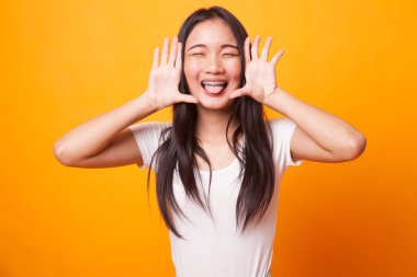 Genç Asyalı kadın dilini dışarı parlak sarı zemin üzerine yapışmasını