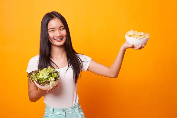 年轻的亚洲妇女与土豆片和沙拉在明亮的黄色背景 — 图库照片