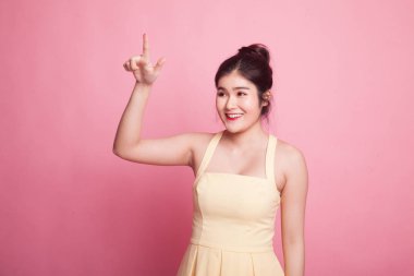 Asyalı kadın pembe arka planda parmaklarıyla ekrana dokunuyor.