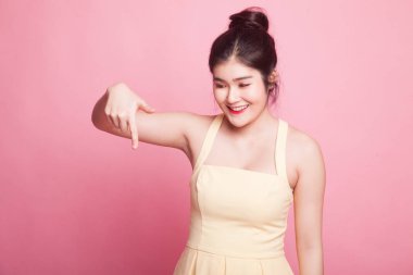 Güzel genç Asyalı kadın pembe arka plandaki boşluğu işaret ediyor.