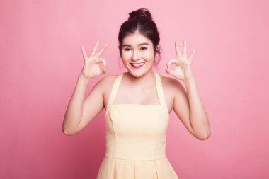 Asyalı kadın çift tamam işareti göster ve pembe arka planda gülümse