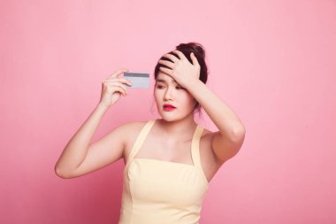 Genç Asyalı kadın baş ağrısı ve pembe arka planda boş bir kart.