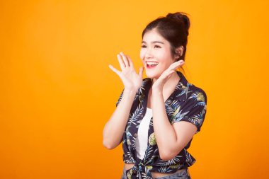 Genç Asyalı kadın şaşırır ve sarı zemin üzerine tropikal gömlek gülümsemek