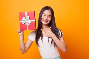 Parlak sarı zemin üzerine bir hediye kutusu ile Genç Asyalı kadın