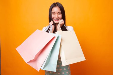 Güzel genç Asyalı kadın ile alışveriş torbaları parlak sarı zemin üzerine