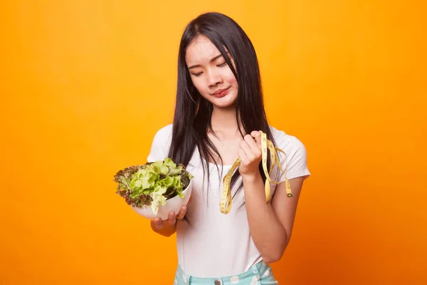 不愉快的亚洲妇女与测量磁带和沙拉在明亮的黄色背景 — 图库照片