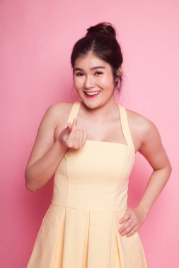 Genç Asyalı kadın pembe arka planda kalp işareti gösteriyor.