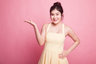 Pembe arka planda eli olan genç bir Asyalı kadın var.