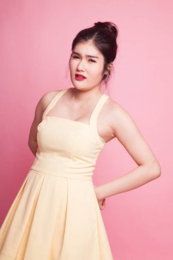 Genç Asyalı kadının pembe arka planda sırt ağrısı var.