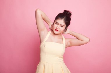 Uykulu genç Asyalı kadın pembe arka planda esniyor.