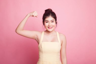 Güzel genç Asyalı kadın pembe arka planda kaslarını esnetiyor.