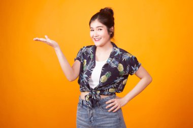 Genç Asyalı kadın eliyle mevcut tropikal forması sarı arka plan