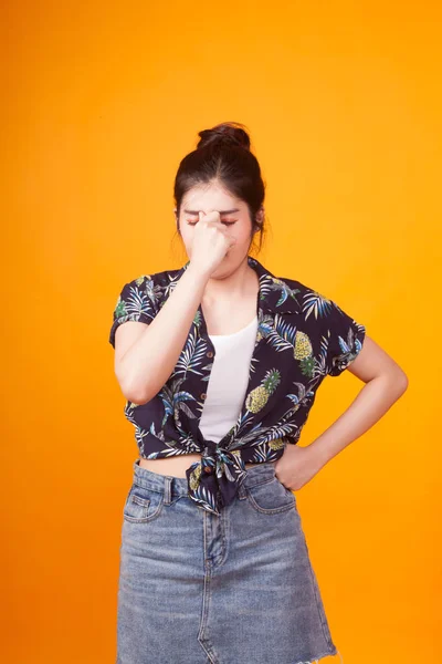 Young Asian woman got sick and  headache in  tropical shirt on yellow background