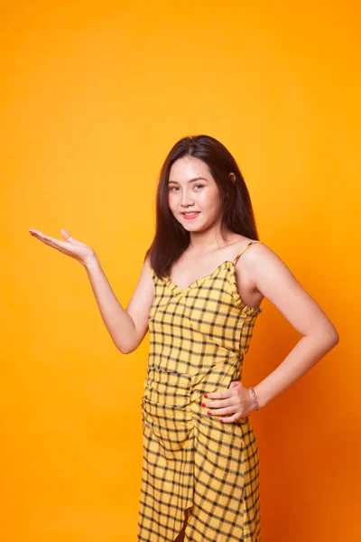 黄色の背景に彼女の手で現在若いアジア女性 — ストック写真