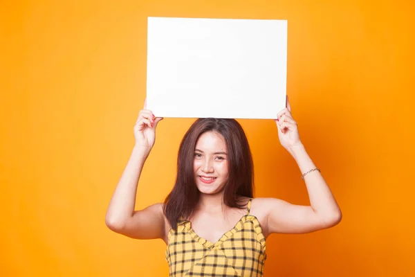 黄色の背景の白い空白記号を持つ若いアジア女性 — ストック写真