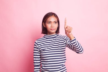 Asyalı kadın pembe arka planda parmaklarıyla ekrana dokunuyor.