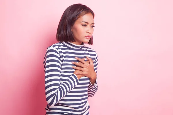 Young Asian woman got chest pain on pink background