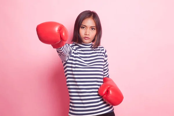 Young Asian woman with red boxing gloves on pink background