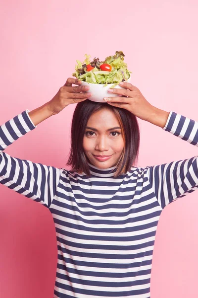 Healthy Asian woman with salad on pink background