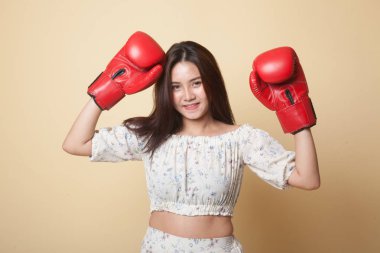 Bej arka planda kırmızı boks eldivenli genç Asyalı kadın.