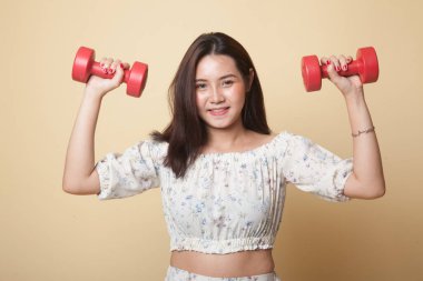 Bej arka planda dambılları olan sağlıklı bir Asyalı kadın.