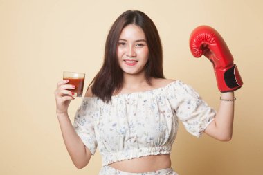 Domates suyu ve Boks eldiveni bej renkli arka plan üzerinde genç Asyalı kadın