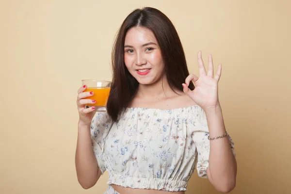 Jovem Mulher Asiática Beber Suco Laranja Mostrar Sinal Fundo Bege — Fotografia de Stock