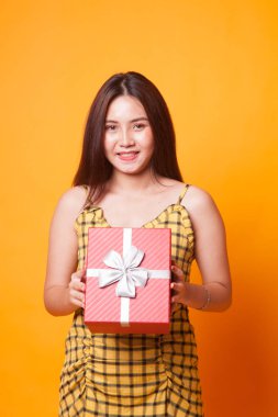 Sarı arka plan üzerinde bir hediye kutusu ile genç Asyalı kadın