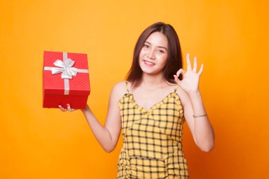 Genç Asyalı kadın Sarı zemin üzerine bir hediye kutusu ile Tamam göster