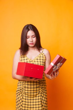 Genç Asyalı kadın açık sarı zemin üzerine bir hediye kutusu